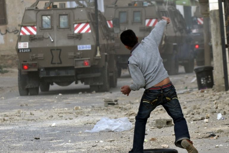Palestinian youth throws stones at military