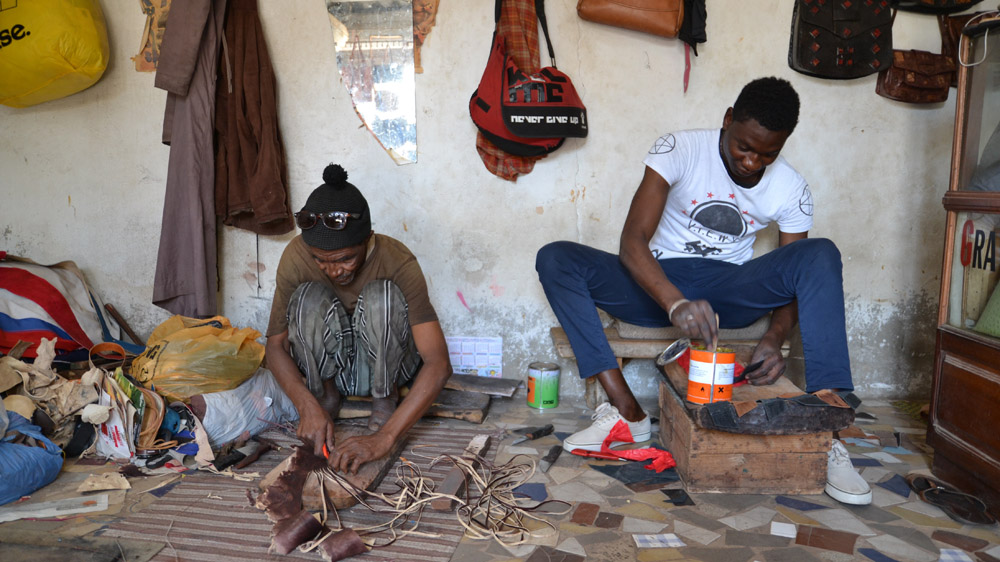 Artisans in Dakar cut details into leather that will eventually be used to make bags [Kait Bolongaro/Al Jazeera]