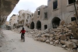 A boy rides a bicycle near damaged buildings in the rebel held area of Old Aleppo