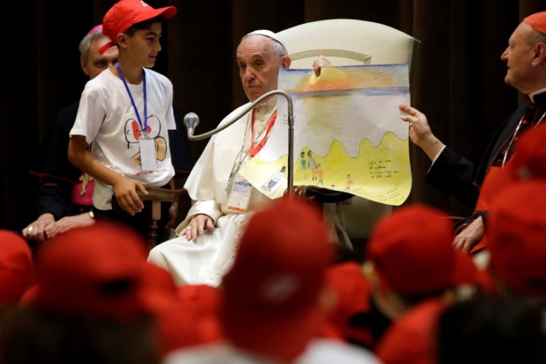 Pope Francis holds a drawing as he meets with youths at the Vatican