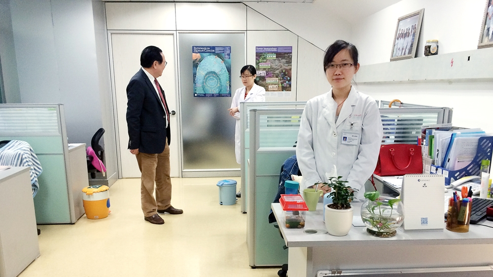 Xu Kecheng talks to PhD students who work as researchers in Fuda Cancer Hospital's laboratories [Simina Mistreanu/Al Jazeera]