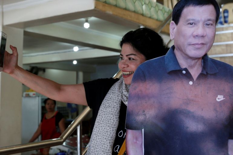 A woman takes a selfie with a cut-out image of leading presidential candidate Duterte at a restaurant in Davao city