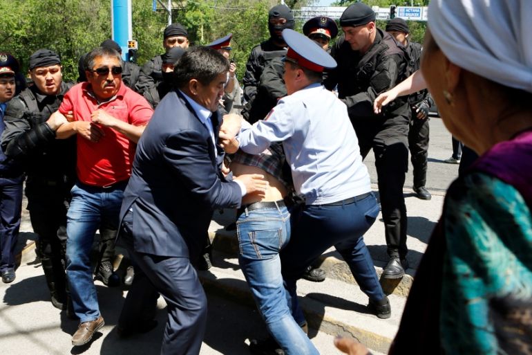 Riot police officers detain demonstrators during a protest in Almaty