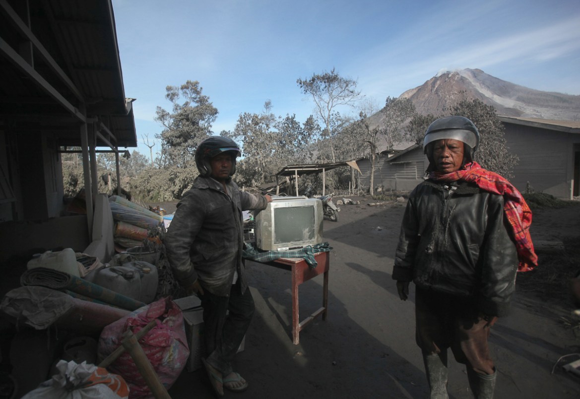 Villagers gather their belongings to evacuate their homes to a safe zone following the eruption of Mount Sinabung in Gamber village, North Sumatra, Indonesia, Sunday, May 22, 2016.