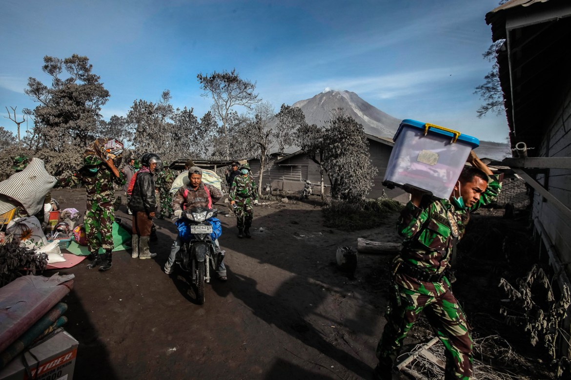 2Indonesian soldiers carry resident''s belongings as they aid in evacuation efforts from a village impacted by the Mount Sinabung eruption at Gamber Village,