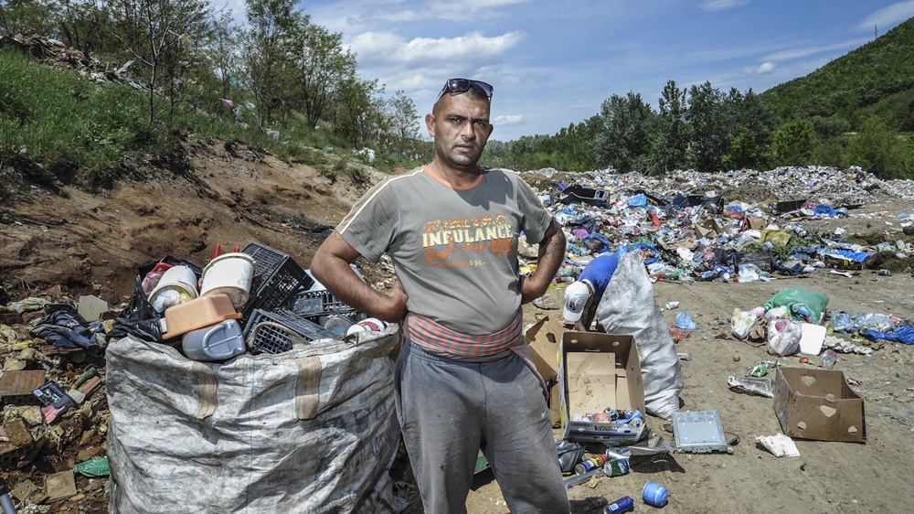 Xhavit Haziri picks through the rubbish in search of recyclables [Atdhe Mulla/Al Jazeera]