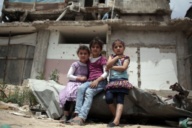 Palestinian girls sit in front of a destroyed house in Shijaiyah neighborhood eastern Gaza City [AP]