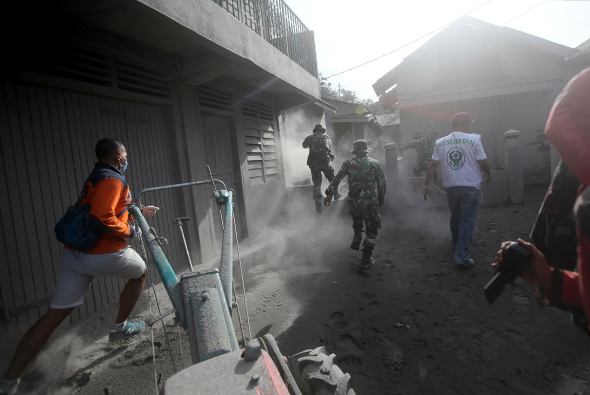 Rescuers rush to help villagers to evacuate their homes following the eruption of Mt. Sinabung in Gamber village, North Sumatra, Indonesia, Sunday, May 22, 2016.
