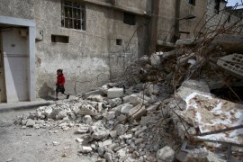 A girl walks near rubble of damaged buildings in the rebel held besieged town of Douma, eastern Damascus suburb of Ghouta