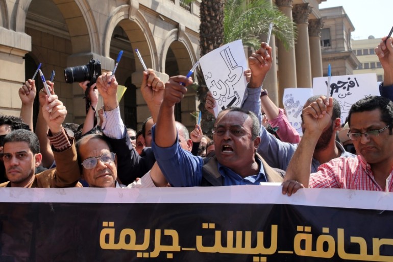Egyptian journalists hold up pens and banner reading in Arabic ''journalism is not a crime'' during a protest outside the Egyptian Press Syndicate in downtown Cairo, Egypt [EPA]