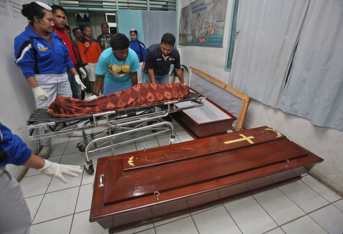 Medical workers prepare to put the body of one of the victims of the eruption of Mt. Sinabung into a coffin at a hospital in Kabanjahe, North Sumatra, Indonesia,