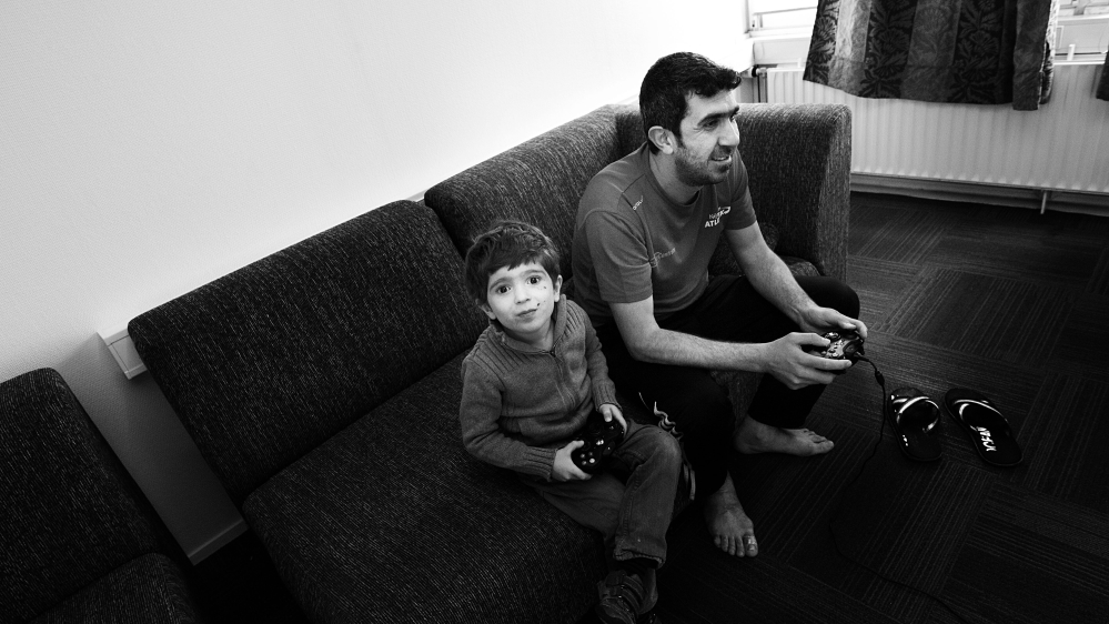 Ammar, Eman's husband, plays on the Xbox with his son Yazan [Mona van den Berg/Al Jazeera] 