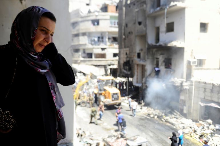 A woman inspects a damaged site after a suicide and car bomb attack in south Damascus suburb of Sayeda Zeinab, Syria [REUTERS]