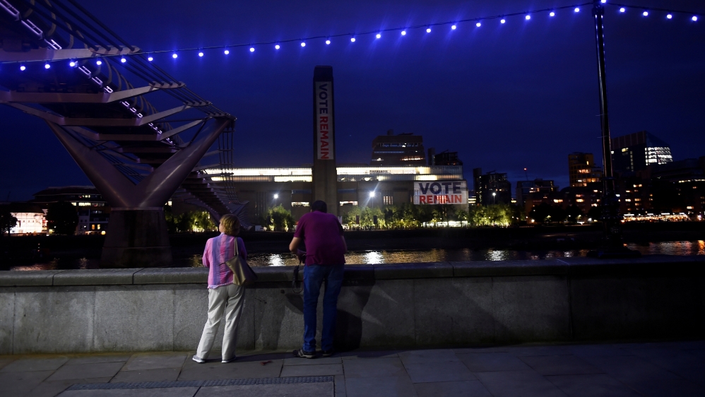 A couple stand by the Thames near a Vote Remain projection on to the exterior of Tate Modern art gallery, in London [Dylan Martinez/Reuters]