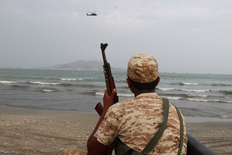Yemeni soldier looks as a UAE military helicopter hover over the sea during the search for the wreckage of a crashed UAE military helicopter off the southern city of Aden, Yemen
