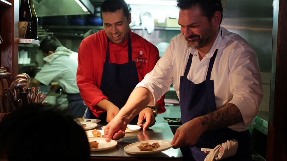 
Stephane Jego, the chef of L'Ami Jean, and Mohammad al-Khaldy, a Syrian chef, work together on one of the collaborative dishes they prepared together during an elaborate and innovative seven-course meal [Micah Garen/Al Jazeera]
