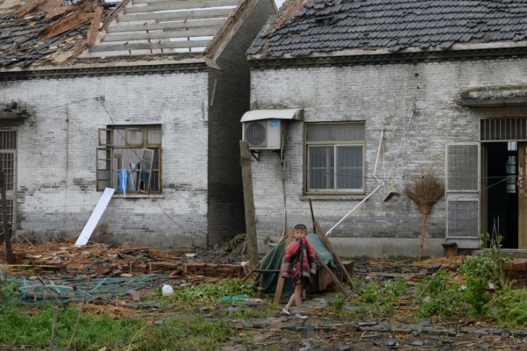 A child walks in front of damaged houses after a tornado hit Yancheng