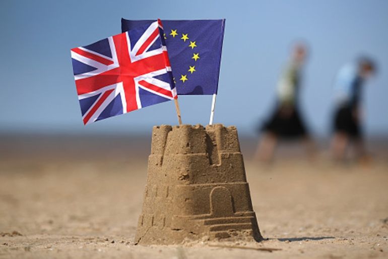 The flag of the European Union and the Union flag sit on top of a sand castle on a beach in Southport, United Kingdom [Getty]