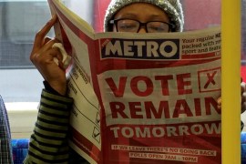A woman reads a newspaper on the underground in London with a ''vote remain'' advert for the BREXIT referendum