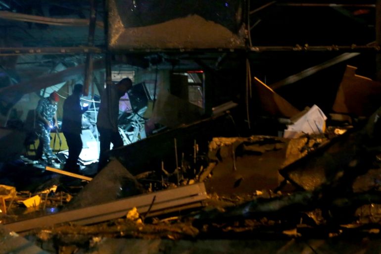 Policemen inspect the damage at the site of an explosion at the headquarters of the Lebanese Blom Bank in Beirut