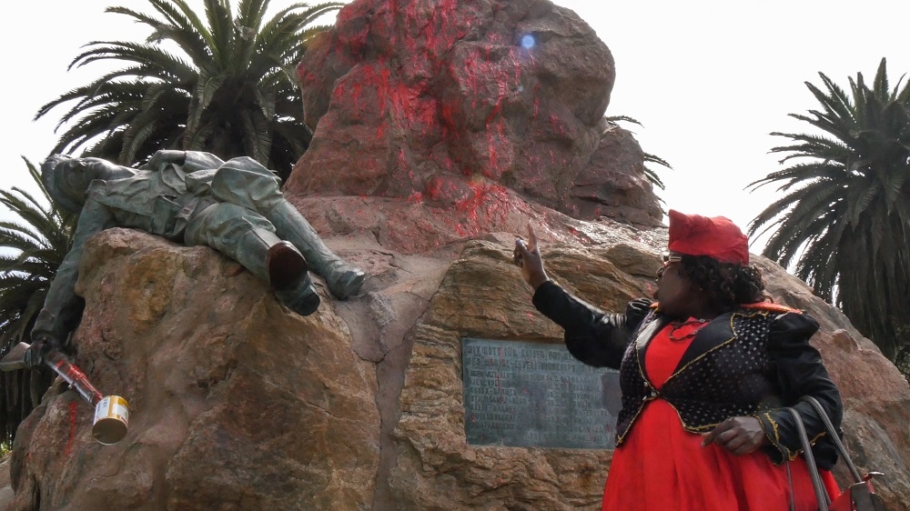 A Herero woman stands in front of a defaced German colonial monument in Swakopmund during a rally in April 2016 [Alexander Honisch/Shiri Media]