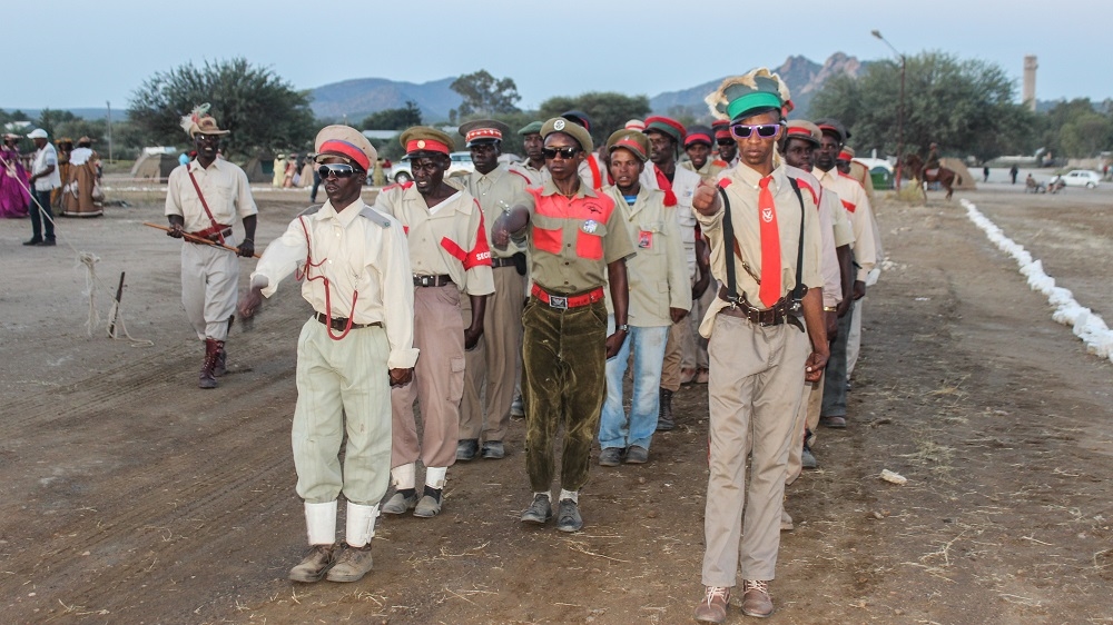 Ovaherero men, dressed in military fatigues to honour their fallen ancestors, march at a commemorative event in Okahandja in August 2015 [Kuzeeko Tjitemisa/Al Jazeera]
