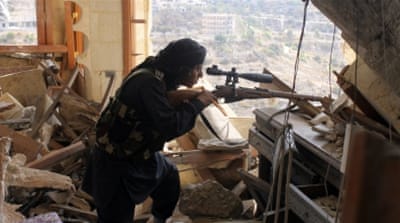 A Syrian fighter aims his weapon as he takes up a defensive position in the Idlib countryside [Reuters]