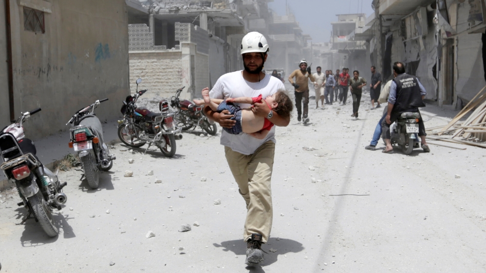 A civil defence member carries an injured girl at a site hit by air strikes in the rebel-controlled area of Maaret al-Numan town in Idlib province [Reuters]