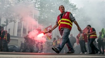A man burns a flare during a demonstration of French rail workers in front of the French employers' union MEDEF's building, Lyon, France [AP]