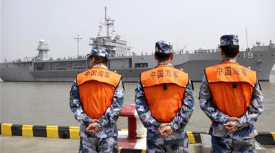 Soldiers from the Chinese People's Liberation Army Navy watch as the USS Blue Ridge arrives at a port in Shanghai [AP]