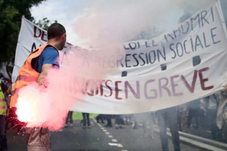 A protester holds a flare in front of a banner reading ''Railroad workers on strike'' during a national demonstration against the Labour Law reform in Paris, France [EPA]