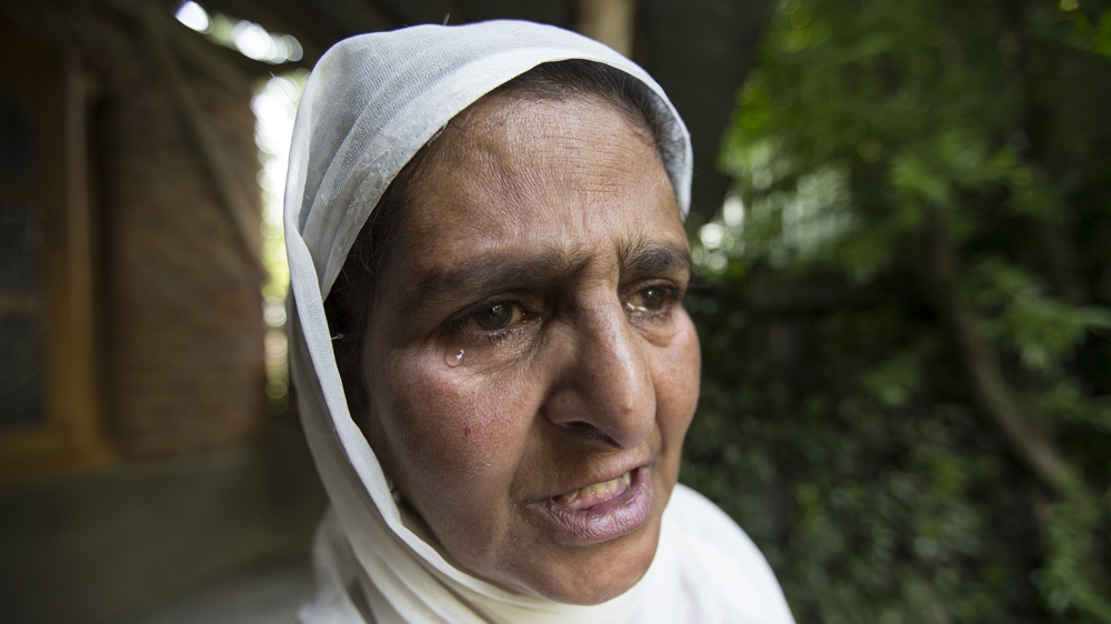 Hafiza cries as she stands at the spot where she says her son was taken [Baba Tamim/Al Jazeera]