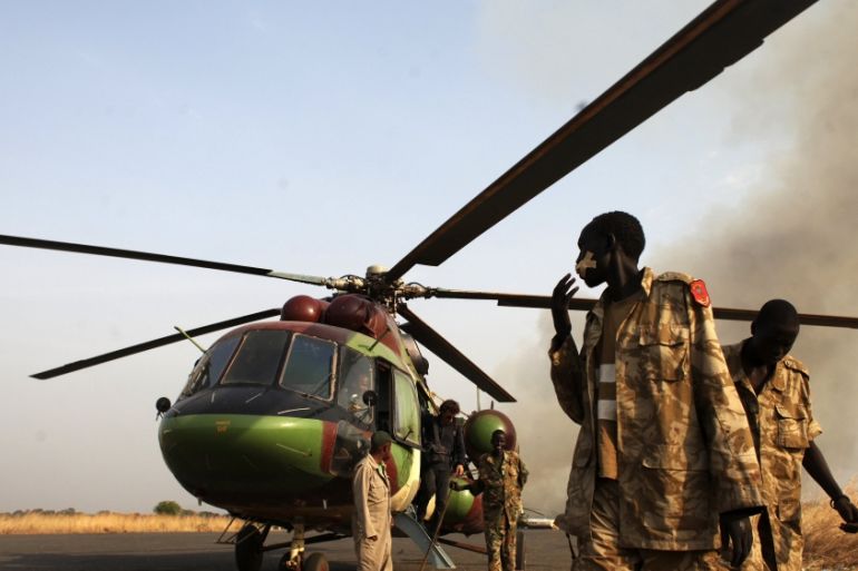 SPLA soldiers and a journalist leave a helicopter after a flight to Bor, in Juba