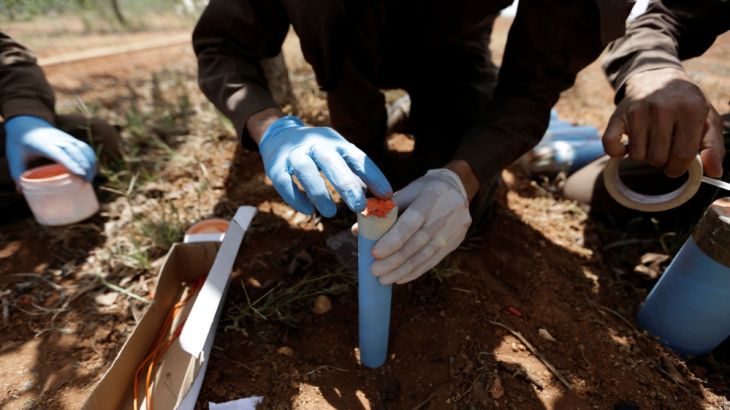 A civil defence member makes a bomb to safely detonate cluster bombs inside a field in al-Tmanah town in southern Idlib countryside