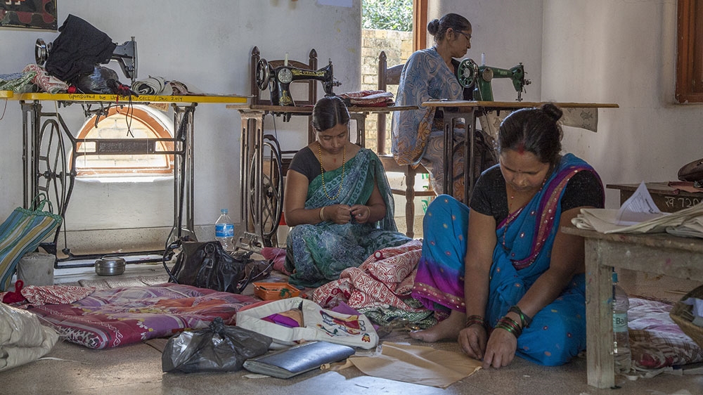 Maithil women sew traditional motifs on to cloth in the JWDC worskhop [Omar Havana/Al Jazeera]