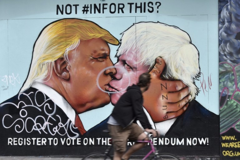 A cyclist takes a look at a painted image of former London Mayor Boris Johnson and US Presidential candidate Donald Trump in Bristol, Britain [EPA]