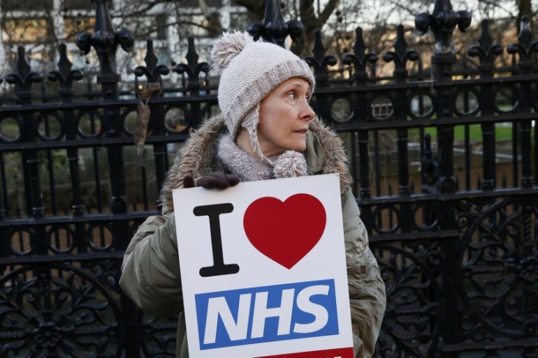 A woman holds a placard that reads ''I Love NHS'' during a strike outside St Thomas'' hospital in central London