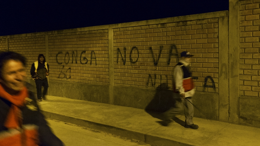 The rondas urbanas on patrol in Cajamarca. On the wall it says 'Conga no va', a protest against a proposed mining project called Conga [Eline van Nes/Al Jazeera]