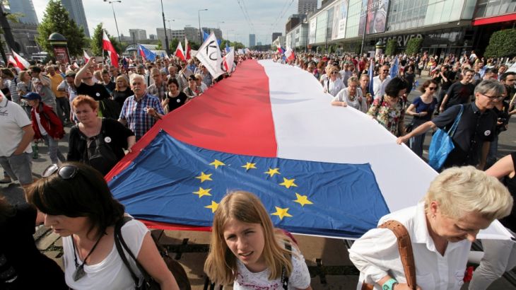 People hold giant Polish and EU flags as they take part in anti-government demonstration organized on the 27th anniversary of the first free non-communist election, in Warsaw