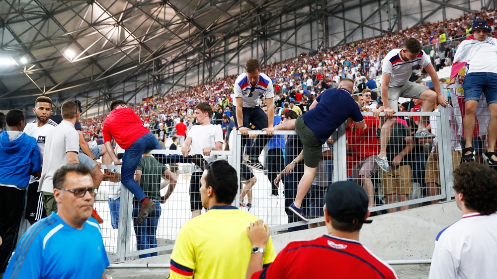Football fans climb over a fence to escape trouble in the Marseille stadium after the match between England and Russia on Saturday night [Reuters]
