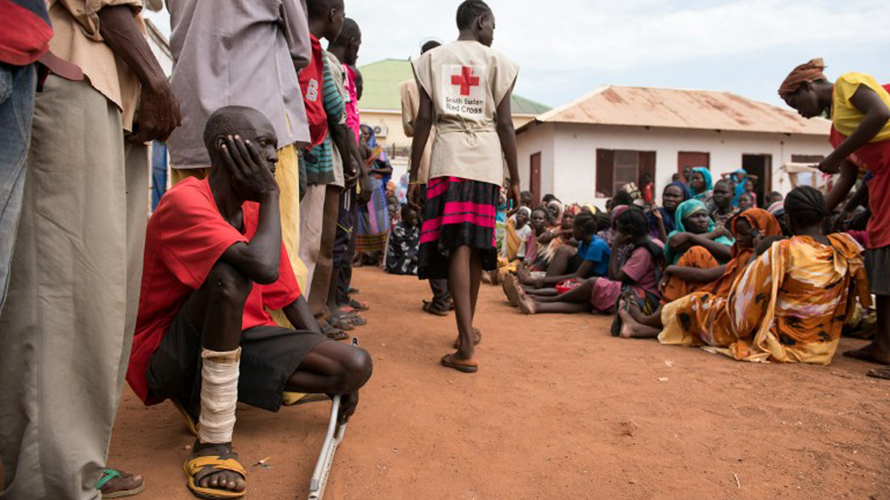 Men and women wait to be registered as displaced persons in a South Sudan Red Cross compound in Wau [Charles Lomodong/AFP]
