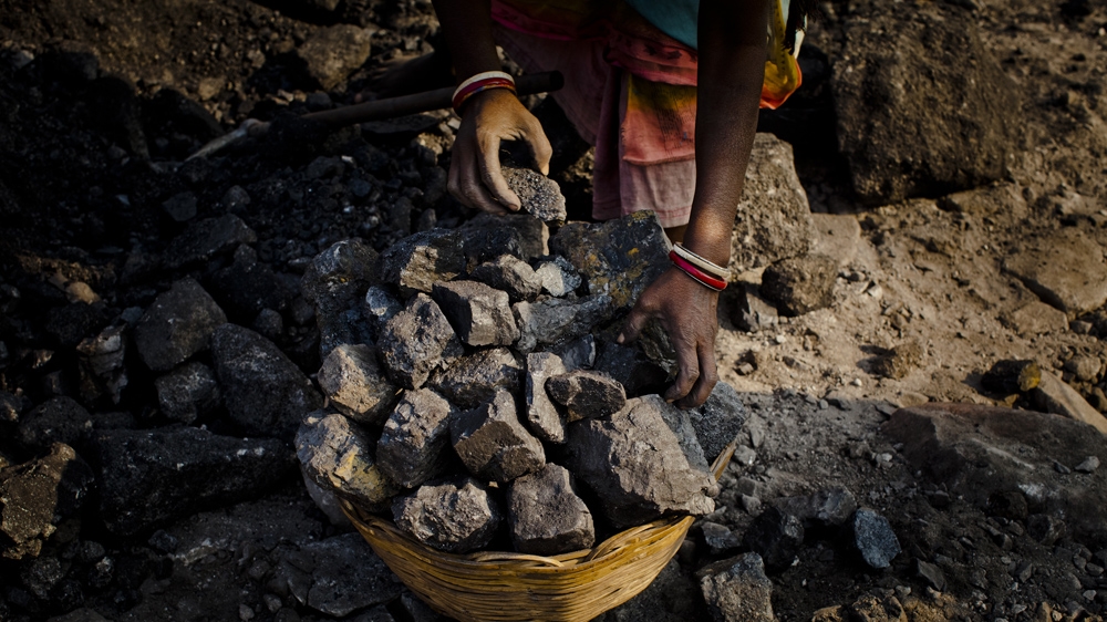 A woman stacks coal into a basket as she and others work to scavenge coal illegally from an open-cast coal mine in the village of near Jharia, India. Villagers in India's Eastern State of Jharkhand scavenge coal illegally from open-cast coal mines to earn a few dollars a day [Daniel Berehulak /Getty Images]