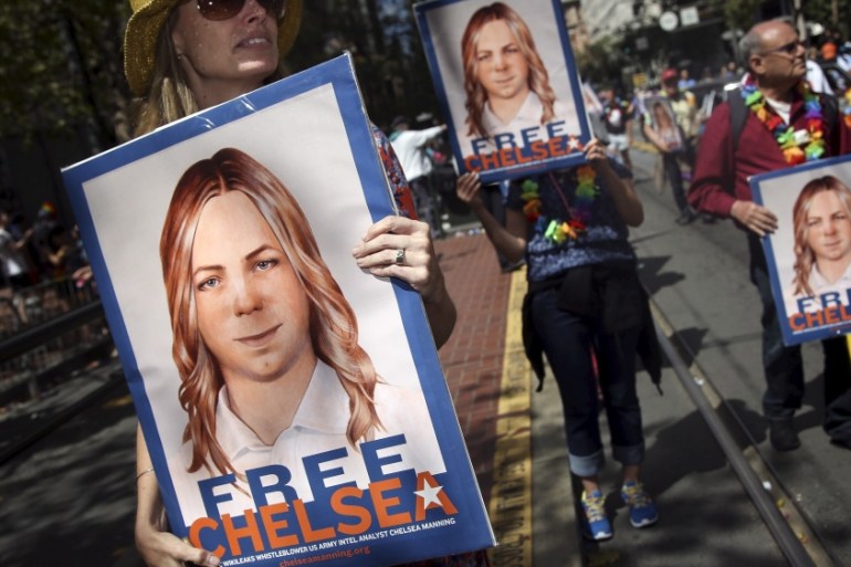 People hold signs calling for the release of imprisoned wikileaks whistleblower Chelsea Manning while marching in a gay pride parade in San Francisco, California