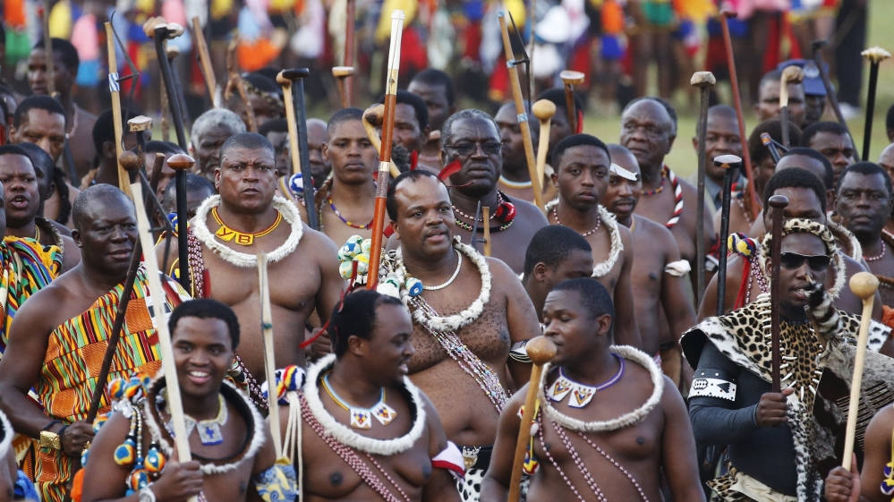 King Mswati III, centre, during the annual ceremony in which female virgins cut reeds and present them to the queen mother. The ceremony provides the king with an opportunity to choose a new wife.  [Siphiwe Sibeko/Reuters]
