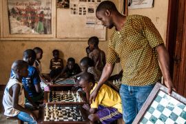 Katende advises one of his students during a match at the Katwe Chess Academy