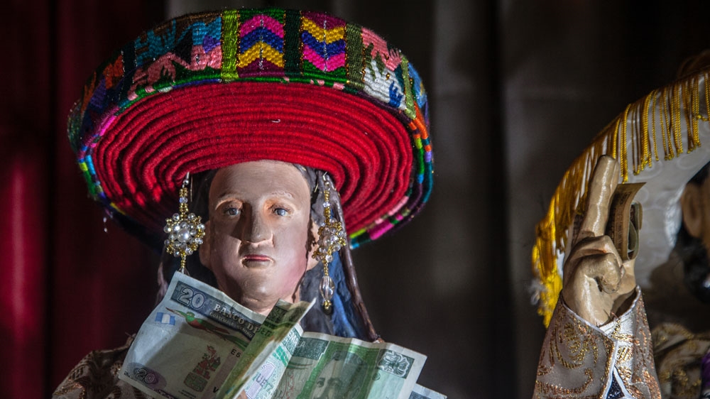 A Catholic saint is dressed in traditional Mayan garb, including a red xk'op hat often worn by women in the community [Gabriela Campos/Al Jazeera] 