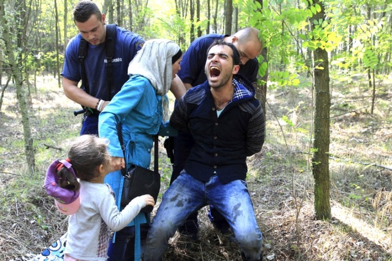 Hungarian policemen detain a Syrian migrant family after they entered Hungary at the border with Serbia, near Roszke