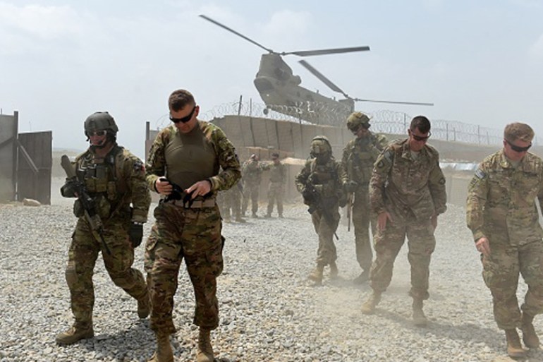 US army soldiers walk as a NATO helicopter flies overhead at coalition base in the eastern province of Nangarhar [Getty]