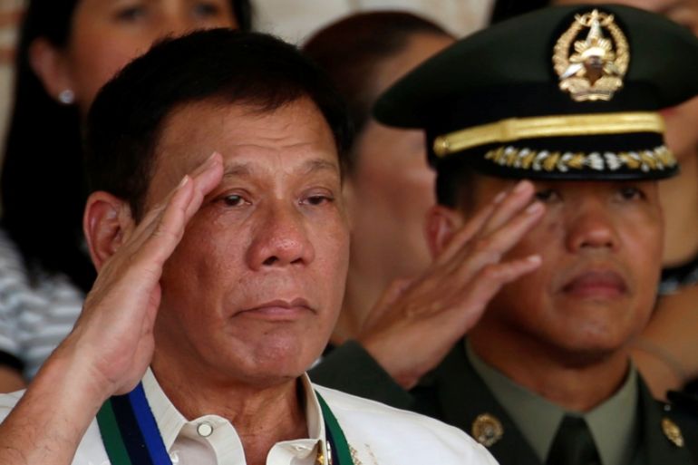 Philippines President Rodrigo Duterte salutes next to a military officer at main military Camp Aguinaldo in Quezon city Metro Manila