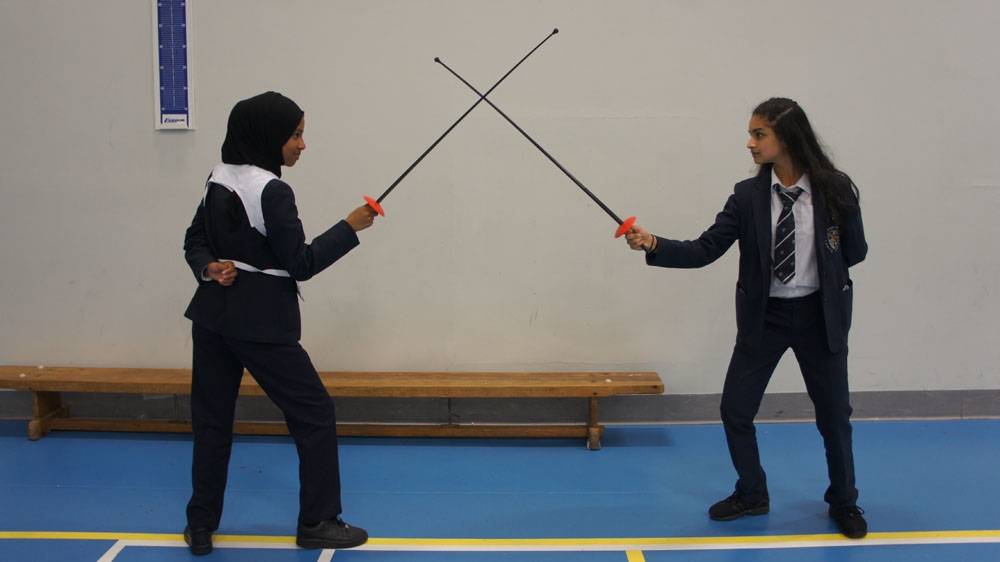 Sarah Saeed, left, and her classmate Seher Chohan are now mentors for other Muslim girls attending the beginner fencing sessions [Zab Mustefa/Al Jazeera]
